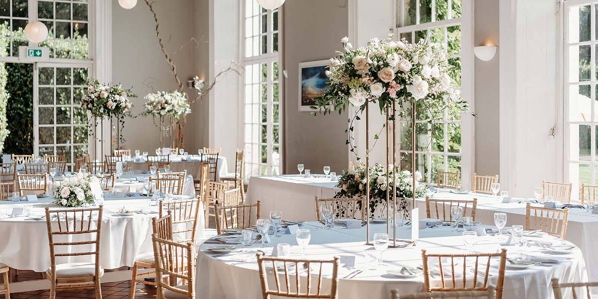 Showstopping Reception Centrepieces A wedding reception at The Orangery, Mount Edgcumbe in Cornwall, with showstopping tall reception centrepieces on the tables, designed and created by Plymputh wedding florist Artem Florum.